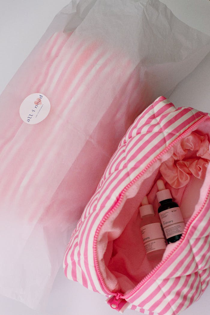 services-01 A top view of a pink striped cosmetic bag containing skincare products, showcasing beauty essentials.