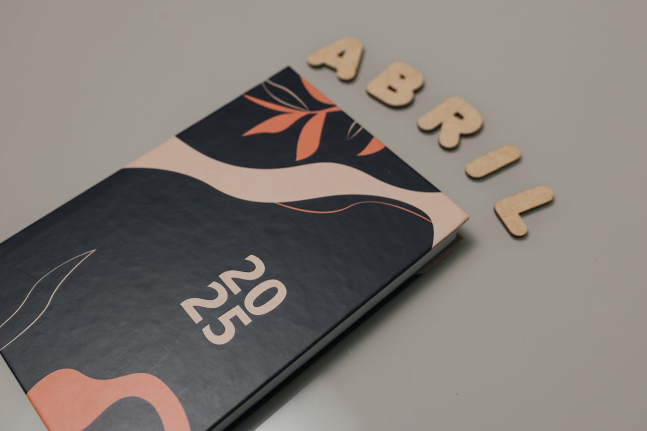 gallery-4 Elegant 2025 planner with abstract cover and wooden letters spelling Abril on a gray surface.
